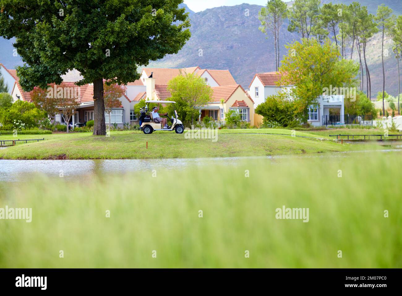 Picturesque. Golfers sitting in a golf cart on a the course in front of the club house. Stock Photo