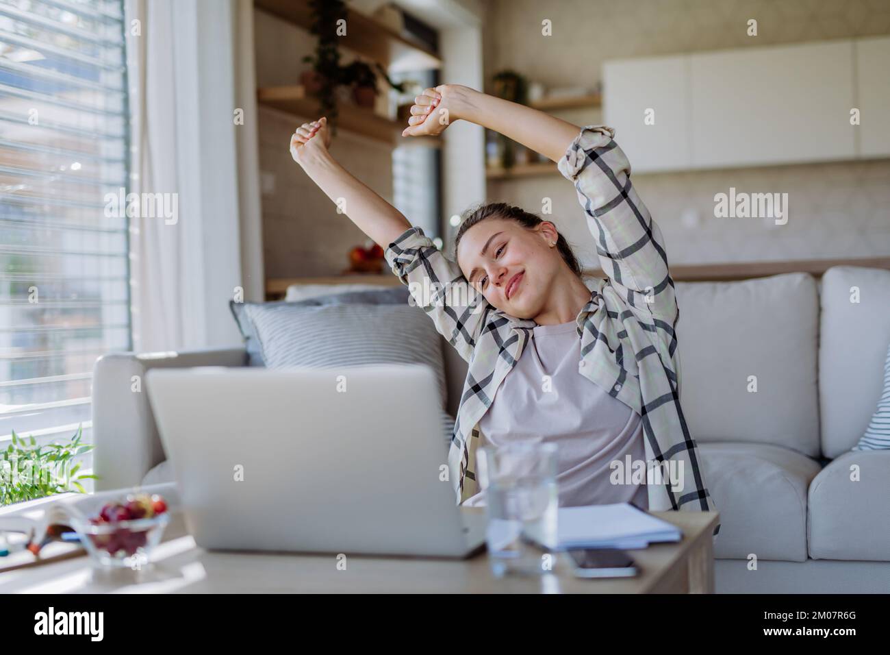 Young woman stretching during homeoffice in her apartment. Stock Photo
