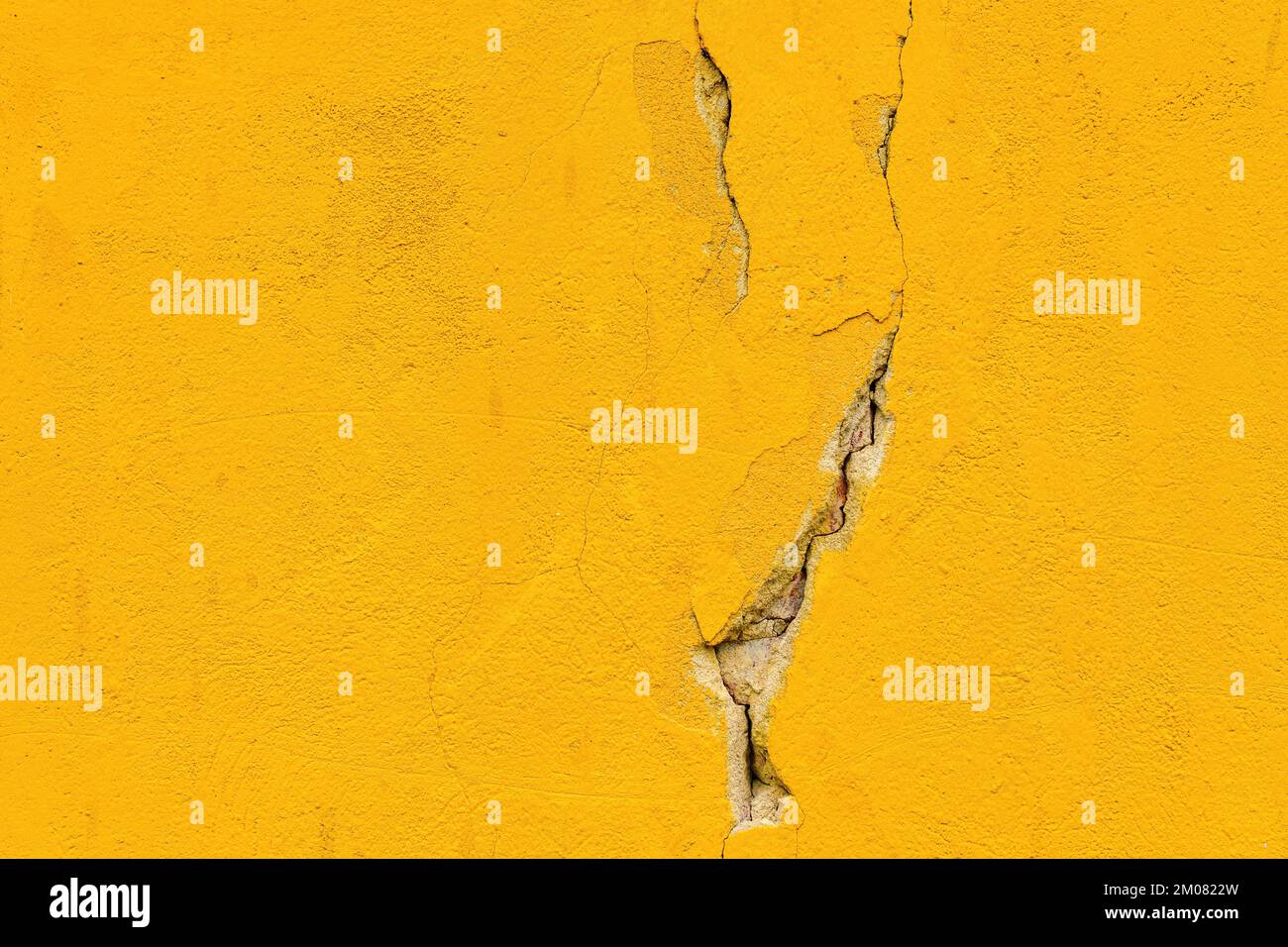 Damaged cracked yellow concrete wall as background and copy space Stock Photo