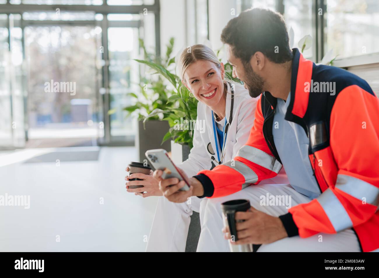Rescuer having break and talking with doctor colleague, at hospital corridor. Stock Photo