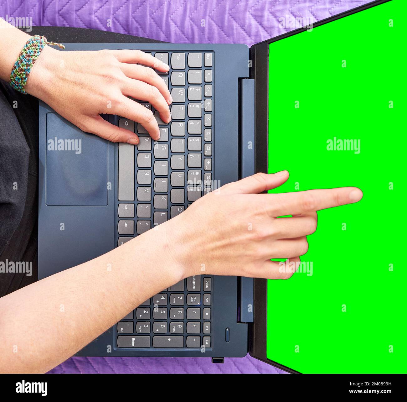 A top view of hands pointing at the green screen of a laptop Stock Photo