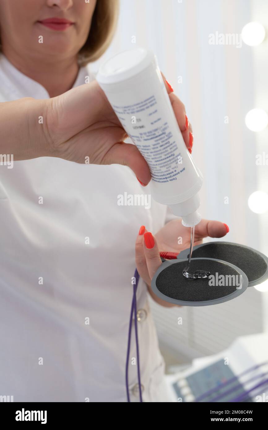 Crop anonymous doctor preparing electronic anti cellulite pads with gel Stock Photo