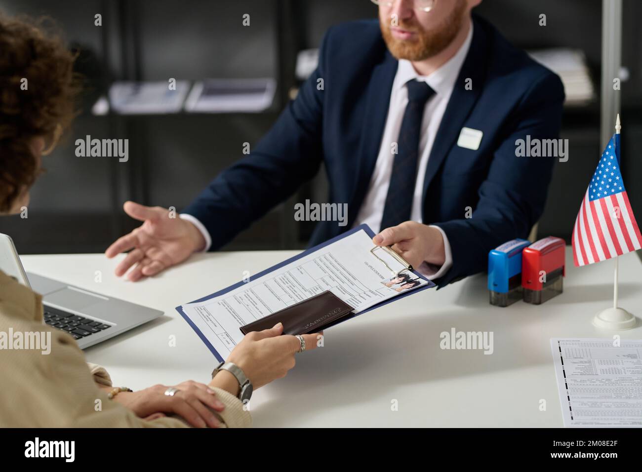 Close up of woman handing visa application form to worker in US embassy office Stock Photo
