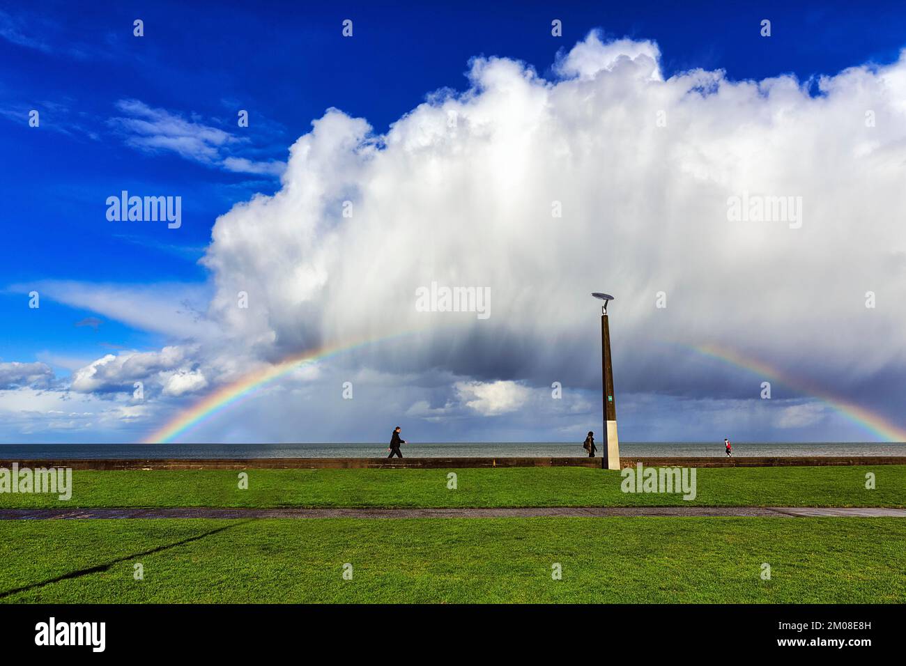 Pedestrians on seafront, dramatic cloudy sky with rainbow, Bray, Wicklow, Ireland, Europe Stock Photo