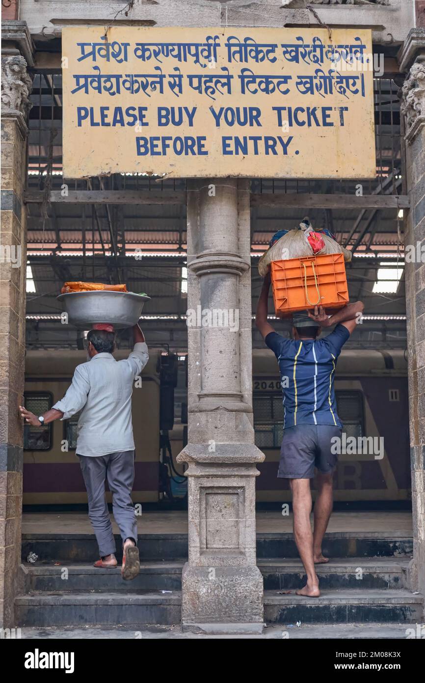 Porters with baskets of fish on their heads entering Chhatrapati Shivaji Maharaj Terminus (CMST), in Mumbai, India, to forward the baskets by train Stock Photo