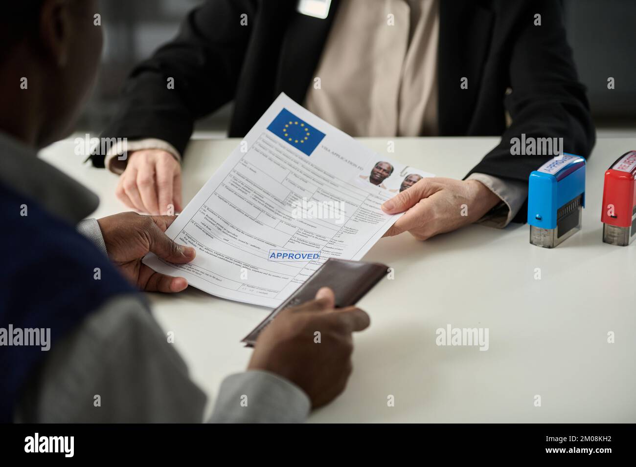 Close up of unrecognizable consulate worker handing approved visa application form to black man in office Stock Photo