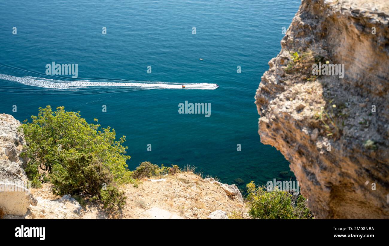 View from above on the coast of Fiolent, in the bay can be seen a rock in the sea and Inflatable round plateun fon holiday by the sea. Stock Photo