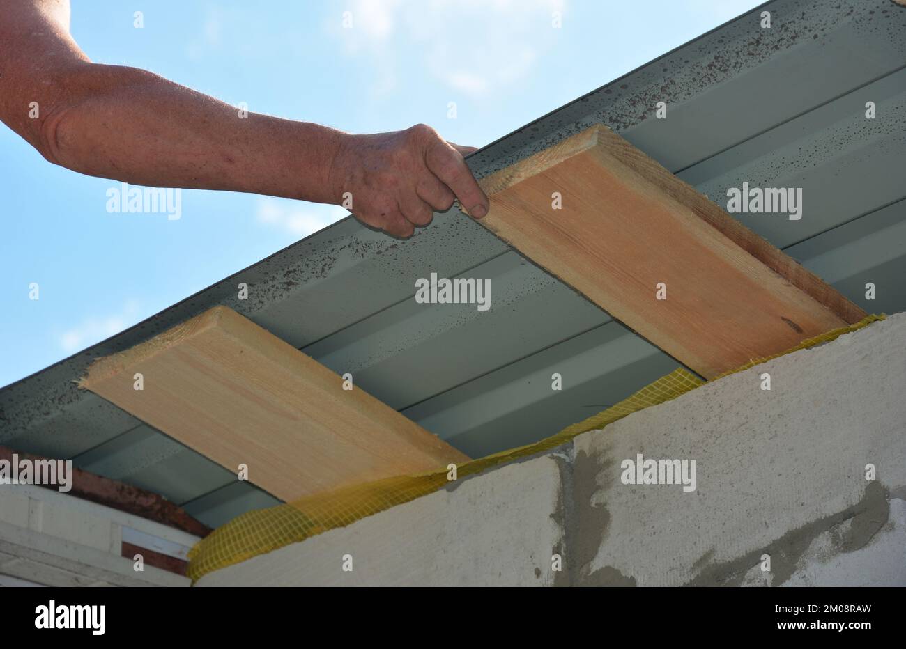 Roofer installing lightweight metal roofing sheets on new house rooftop. Lightweight metal roofing construction. Stock Photo