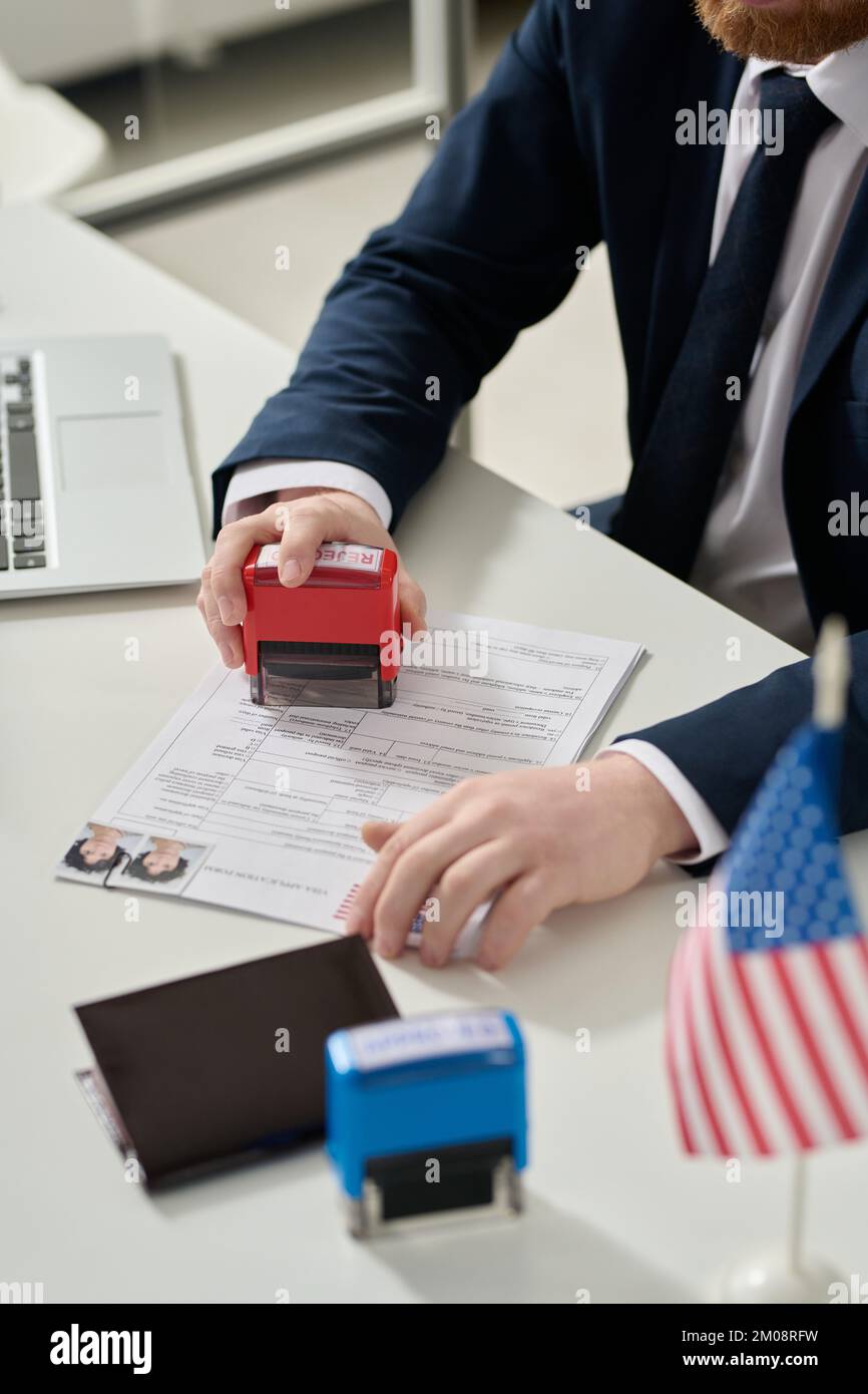 Close up of male worker putting rejected stamp on visa application in US immigration office Stock Photo