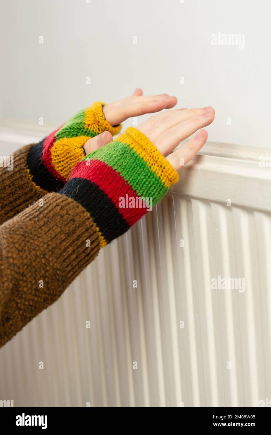 Close up of hands in fingerless gloves warming up against a gas ...