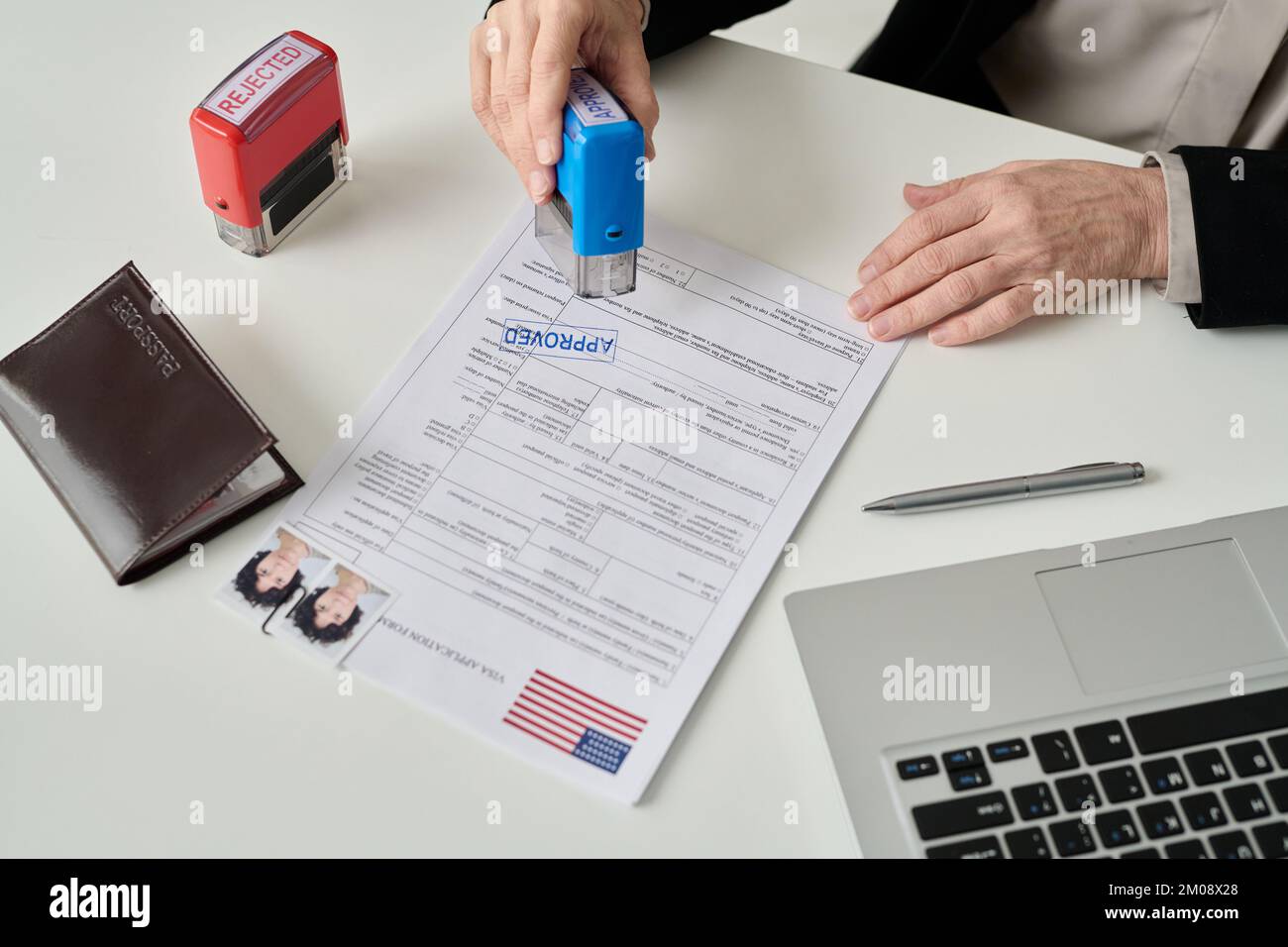 Close up of unrecognizable worker putting approved stamp on visa application form in US immigration office Stock Photo