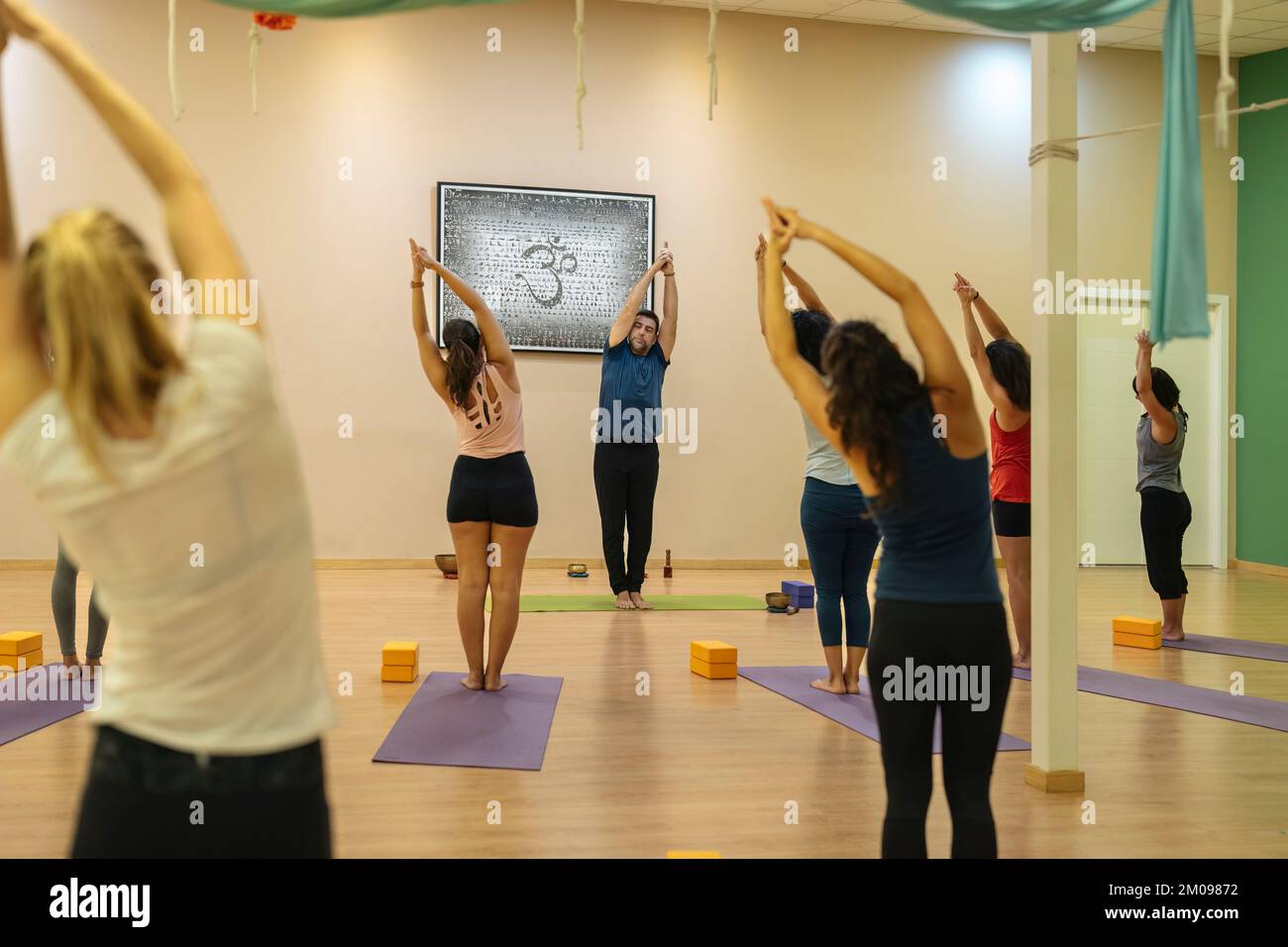 students and instructor in yoga class practicing Nitambasana pose Stock Photo