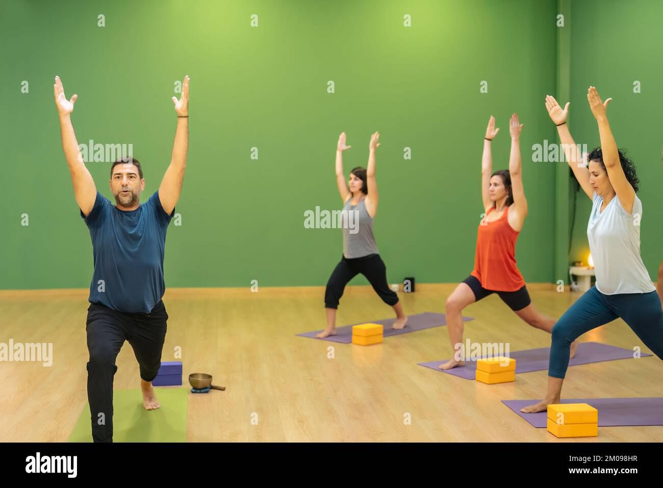yoga teacher teaching a group of students the Ashta Chandrasana pose. Stock Photo