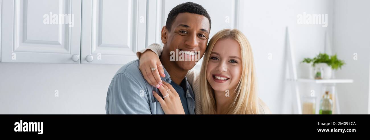 young blonde woman hugging happy african american boyfriend while ...