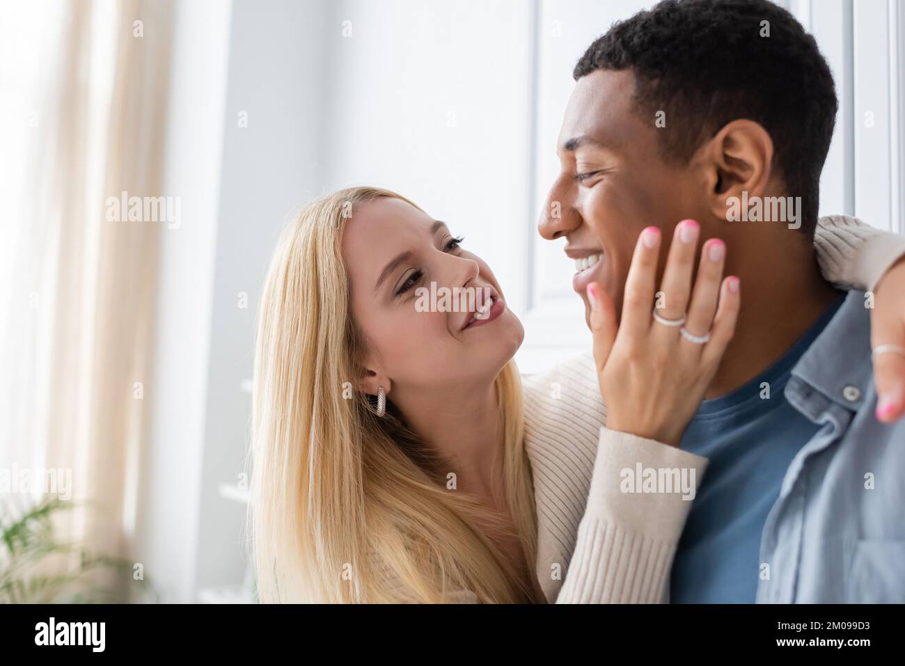 happy blonde woman hugging african american boyfriend and touching his ...