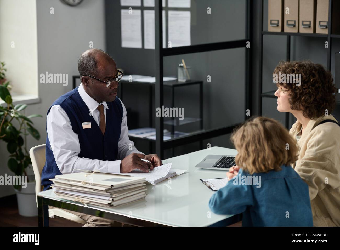 Portrait of senior black man consulting mother with child in insurance agency office Stock Photo