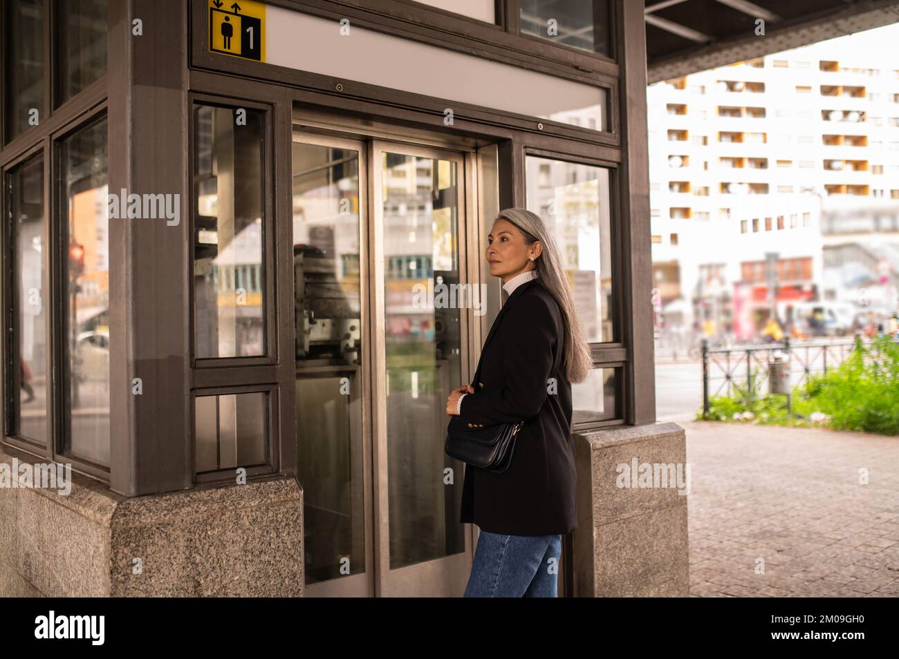 Long-haired woman in a black coat entering subway Stock Photo