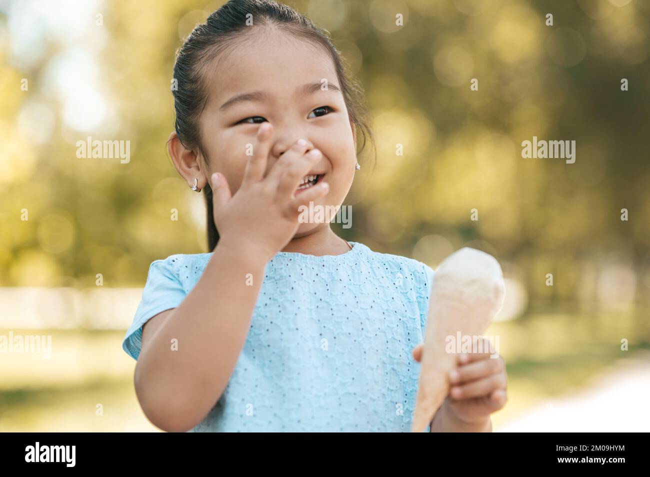 Cute little girl eating icecream and looking contented Stock Photo Alamy