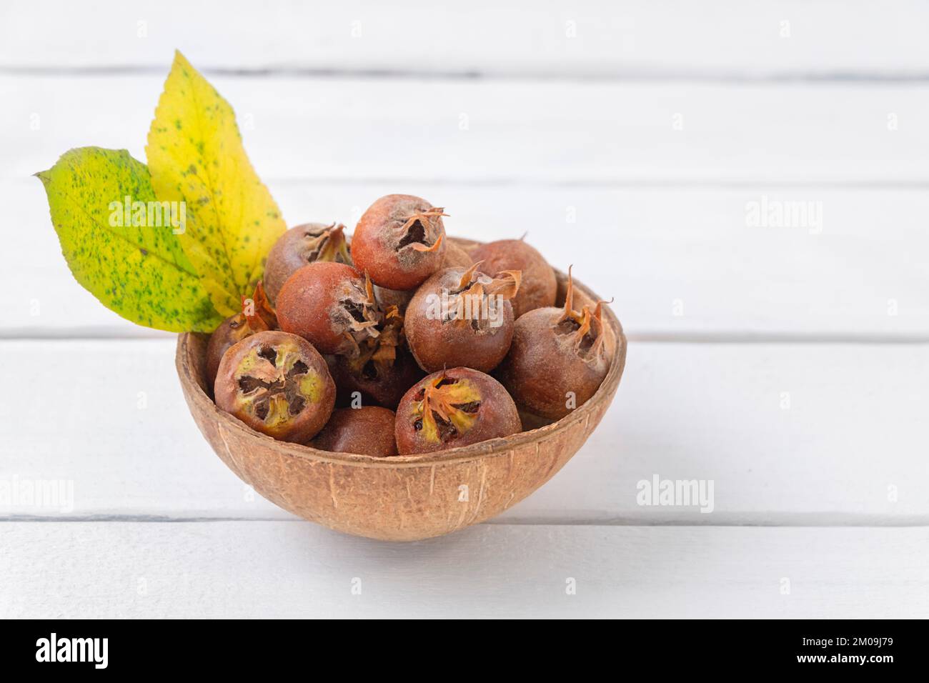 Healthy ripe Medlars on white wooden table with copy space Stock Photo