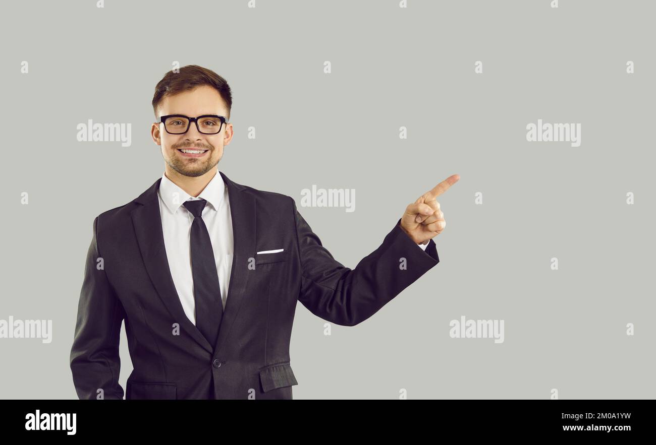 Young positive Caucasian man pointing with finger at copy space dressed in business suit Stock Photo