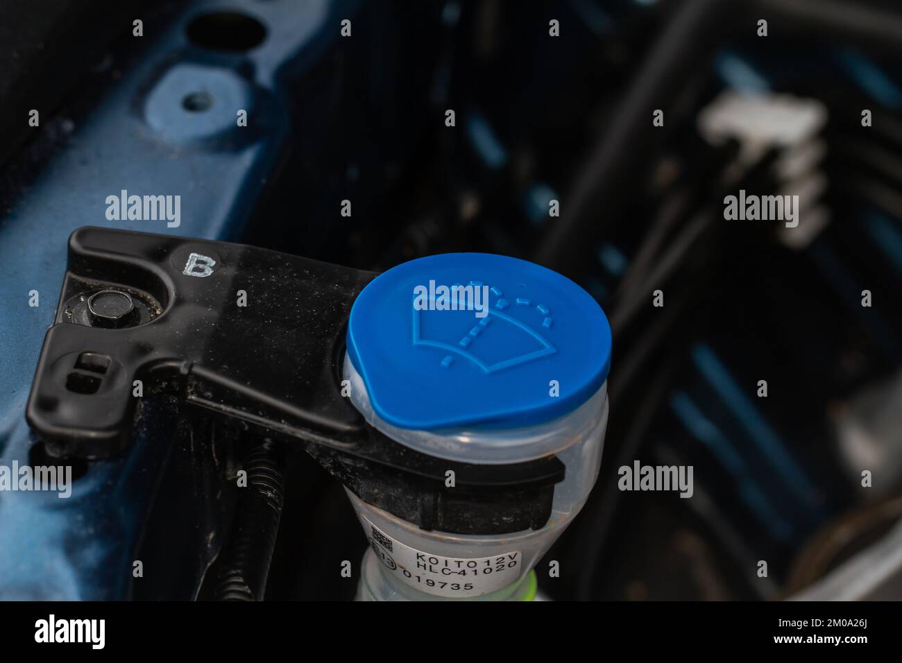 Windshield washer fluid reservoir cap. Windshield washer liquid cap inside a car engine. Closeup