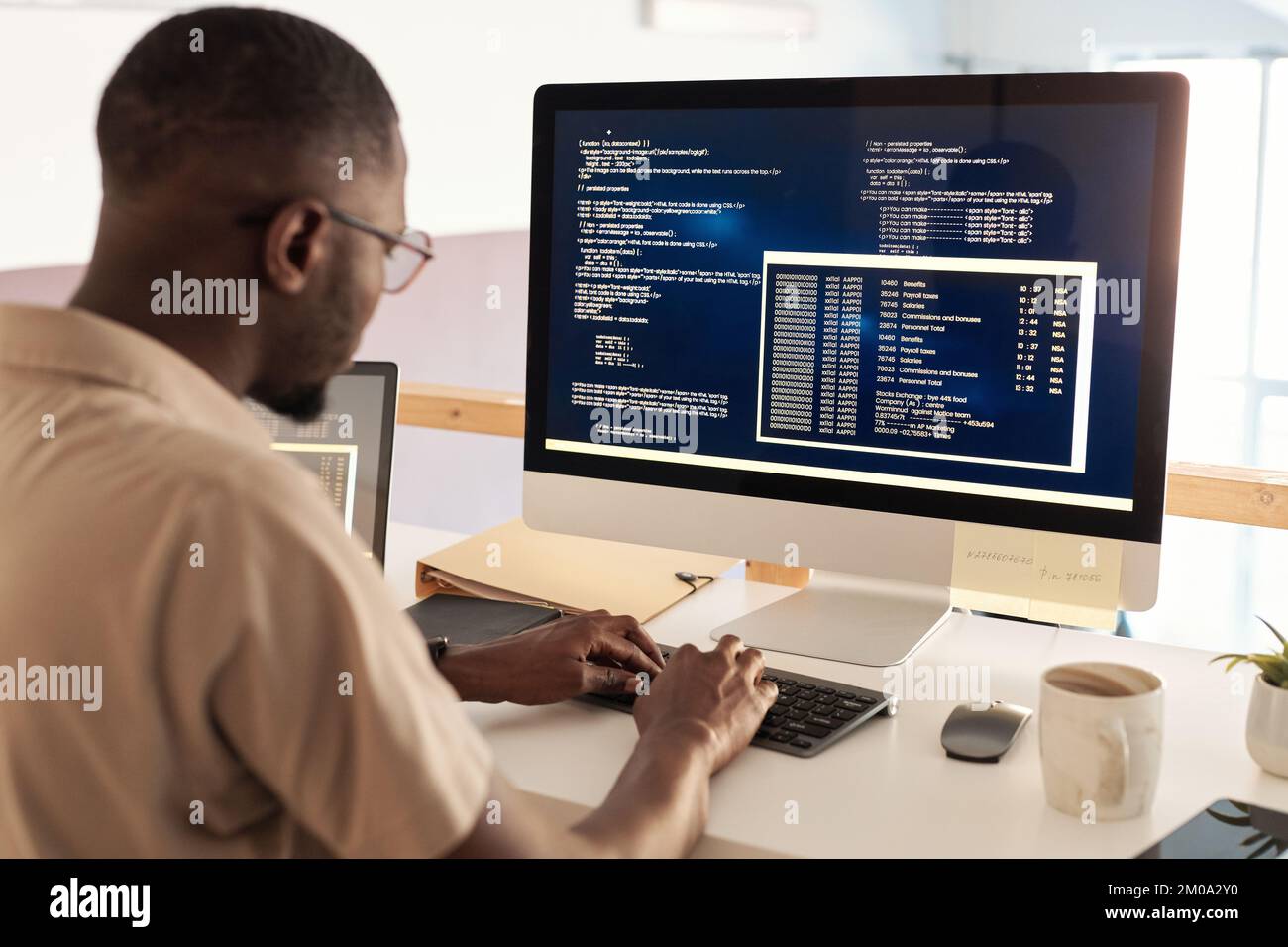 Black developer in glasses debugging software when working on computer in office Stock Photo