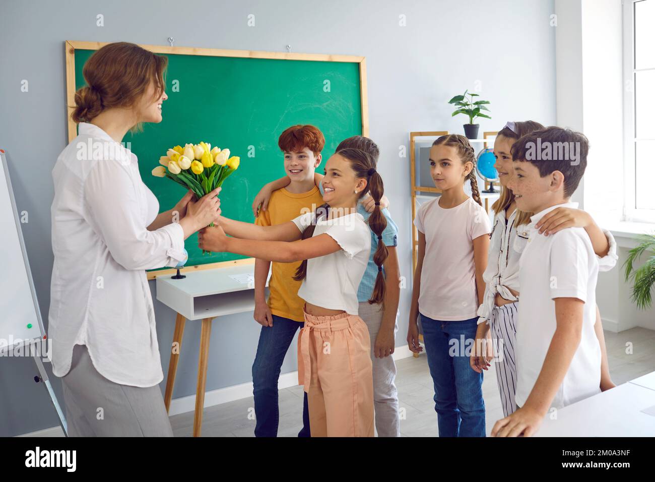 Happy children boys and girls handing flowers to elementary school