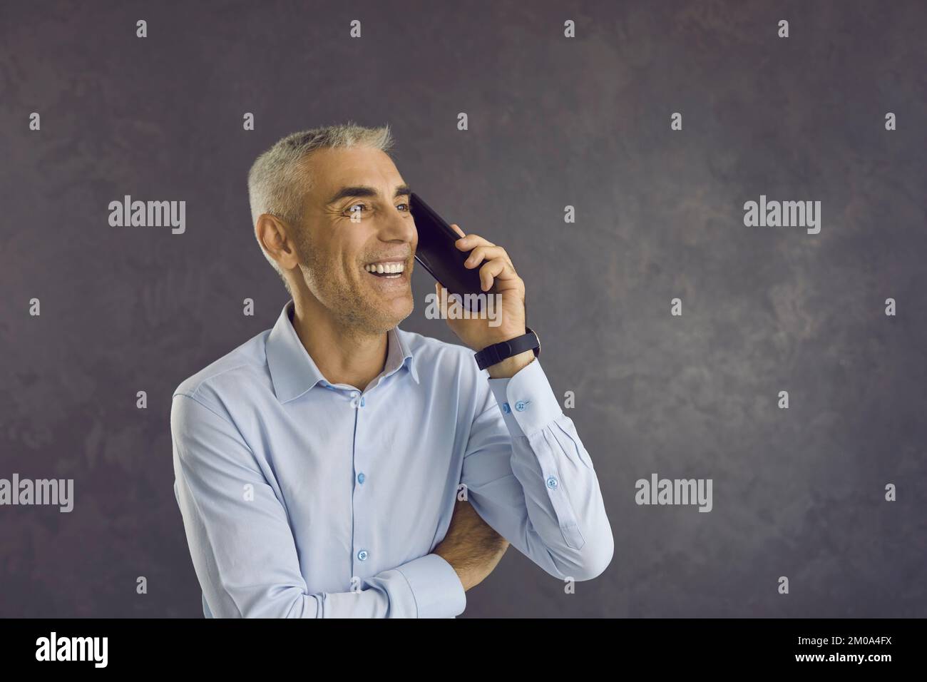 Happy smiling senior man experiencing positive emotions while talking on mobile phone. Stock Photo
