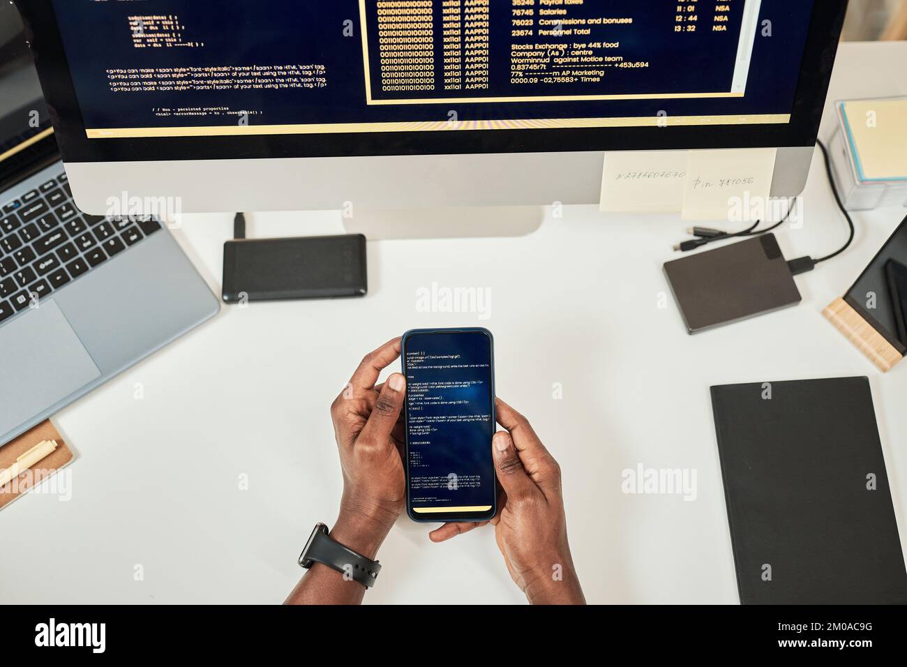 Hands of devops engineer testing mobile app on smartphone, view from top Stock Photo