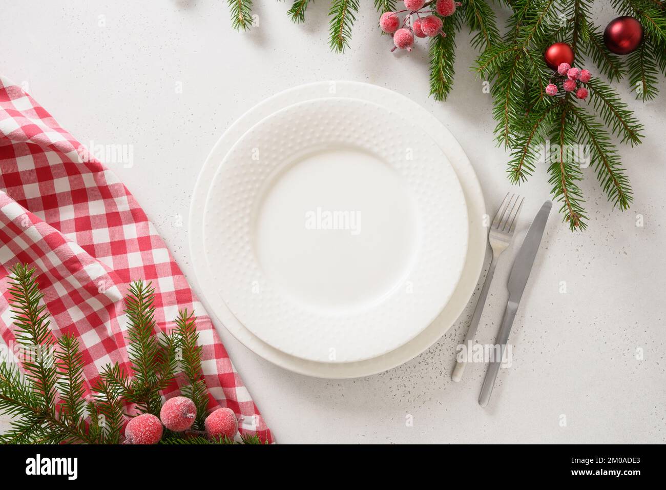 Christmas table setting with red decorative berries on white background. View from above. Copy space. Xmas dinner. Template for festive menu. Stock Photo