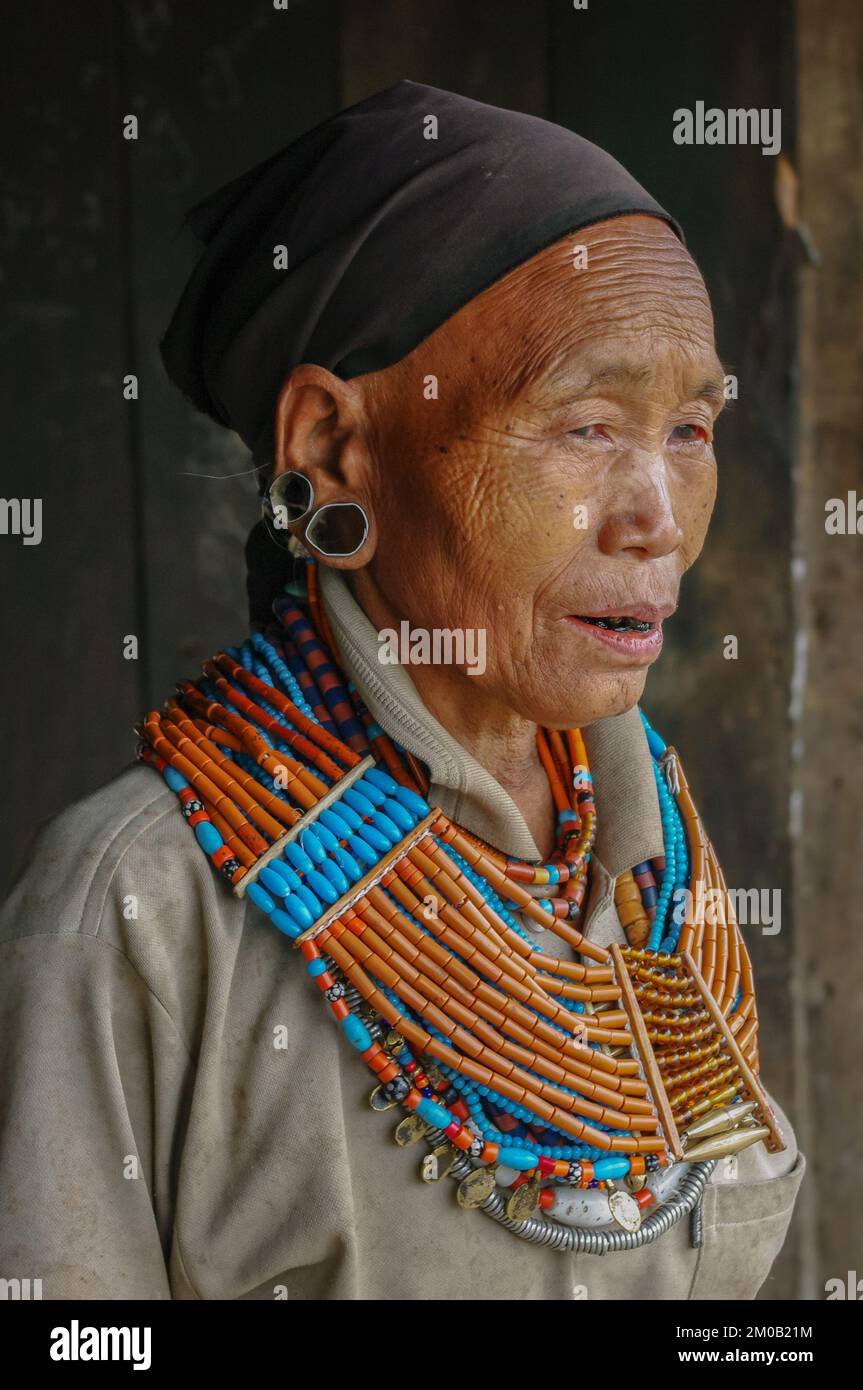 Mon, Nagaland, India - 03 03 2009 : portrait of old Naga Konyak tribe woman wearing traditional necklace and earrings with black head scarf Stock Photo