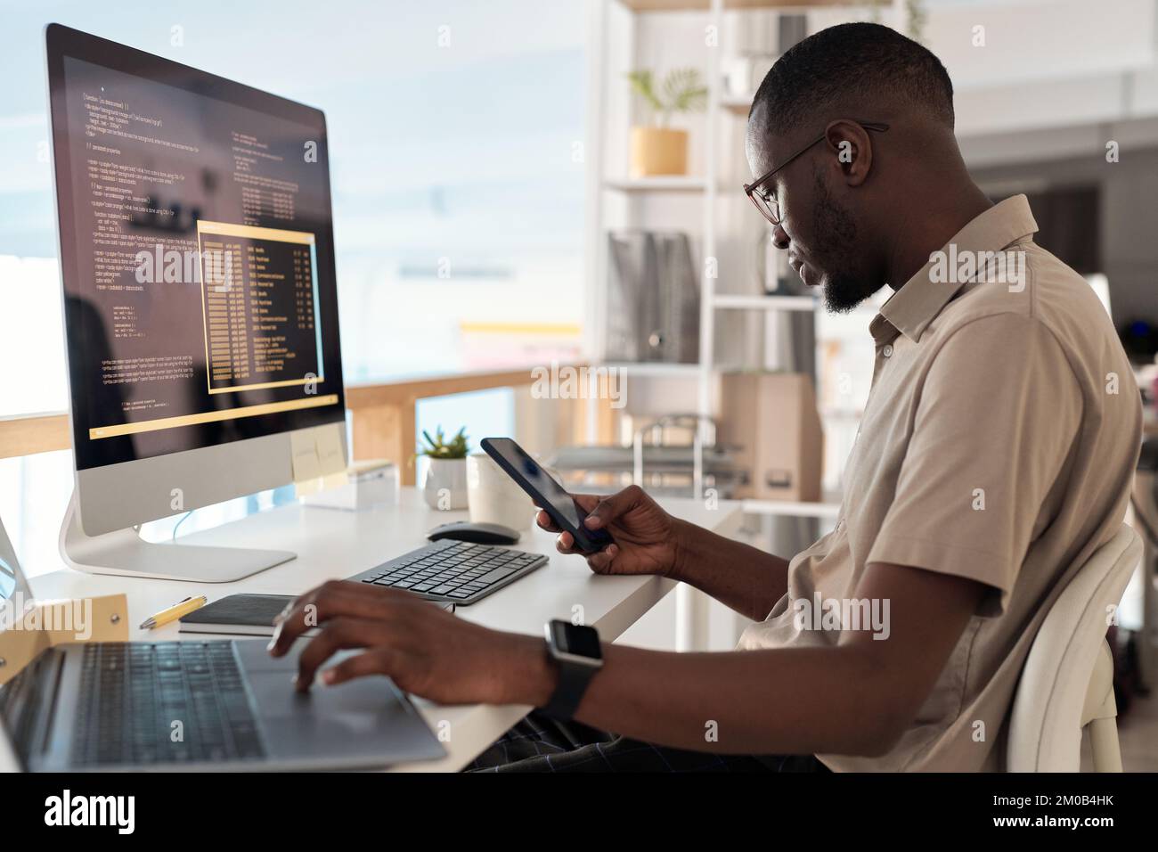 Software developer checking messages and notifications on smartphone Stock Photo