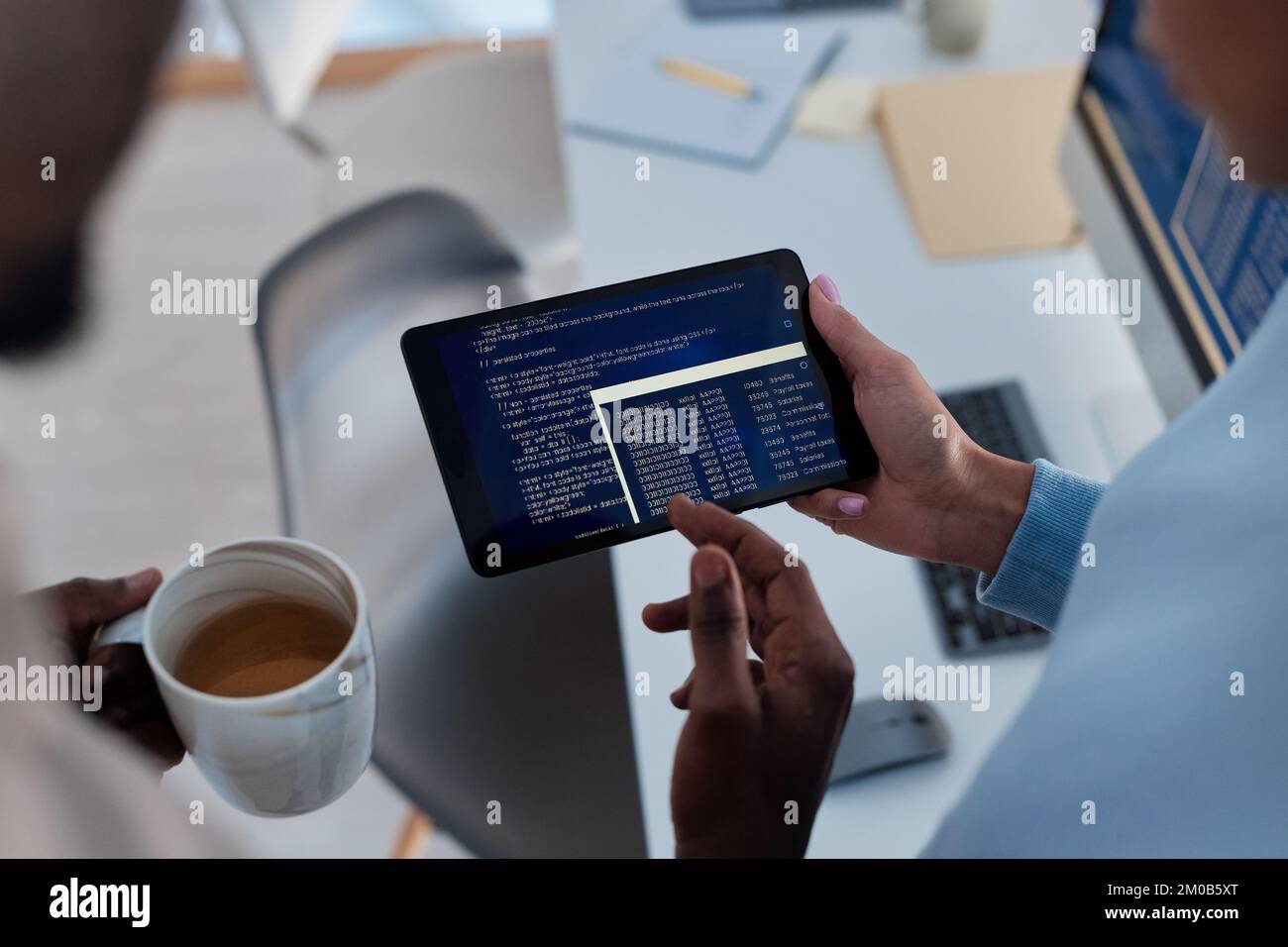 Closeup image of software developers discussing programming code deployed on tablet computer Stock Photo