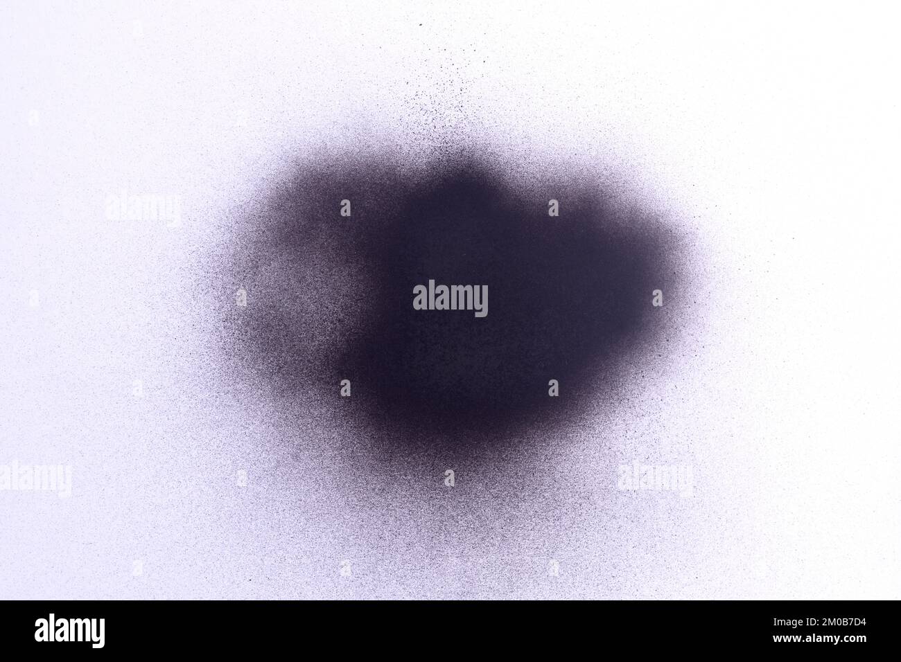 a black spray paint stain on a white paper background Stock Photo - Alamy