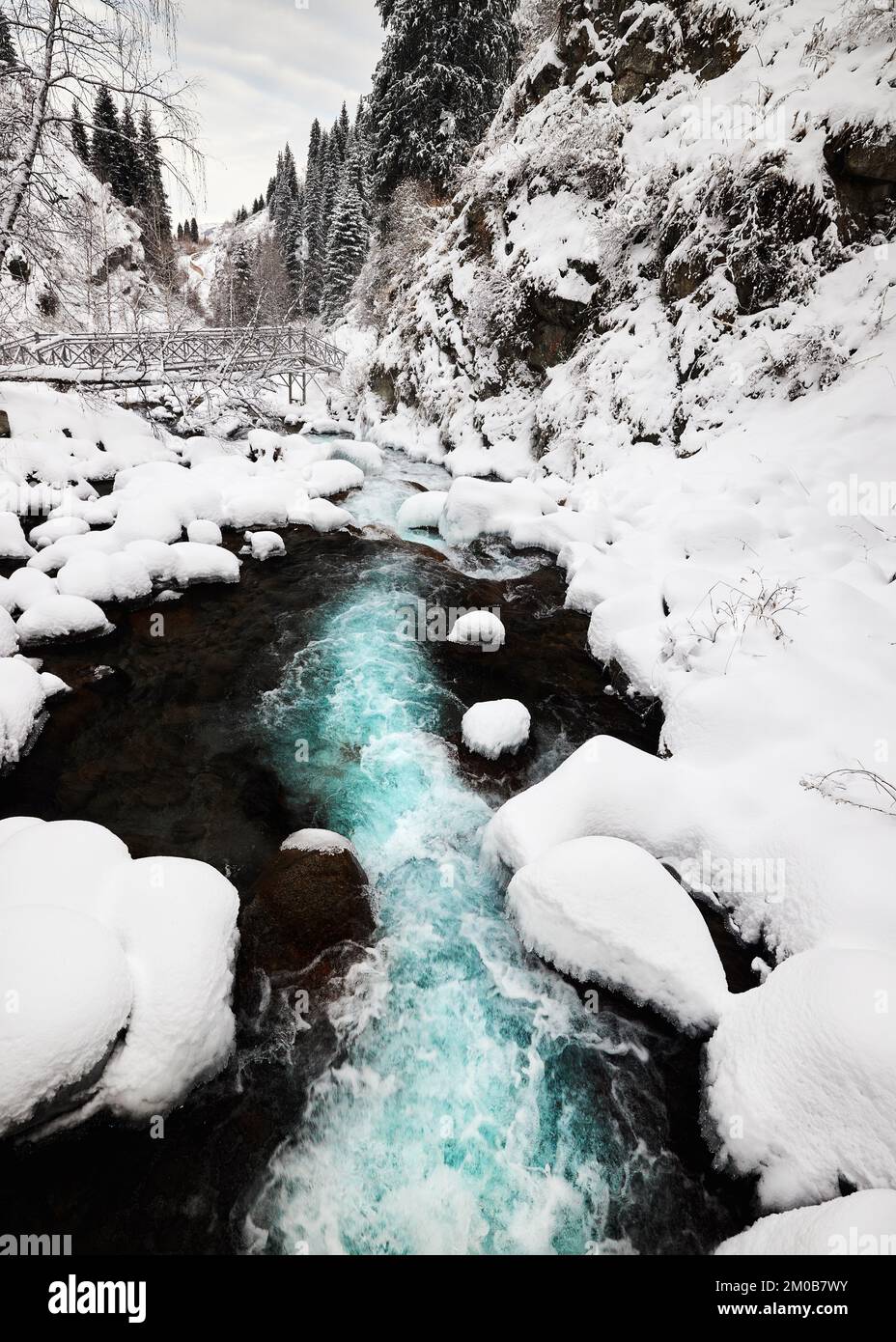 Beautiful scenery of the turquoise mountain water river and bridge near spruce trees forest in Tien Shan, Almaty Kazakhstan. Stock Photo