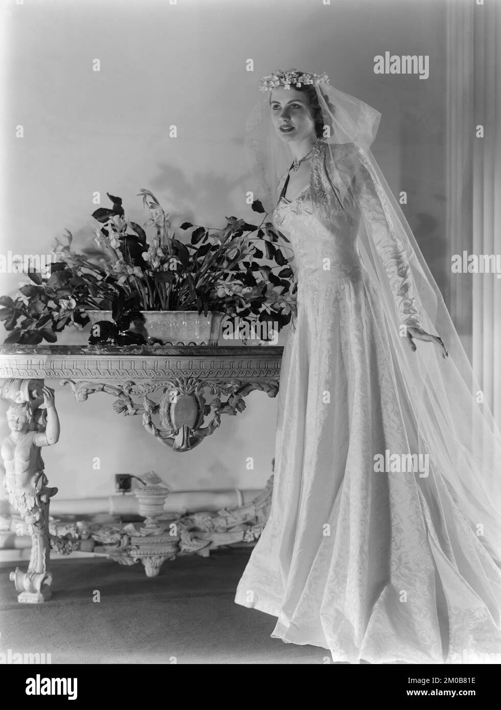 A model working for the Alexandrine Fashion and Model House in Nottingham, England, during the 1950s. She is posing in a studio, wearing one of Alexadrine's latest Wedding Dress designs. Stock Photo