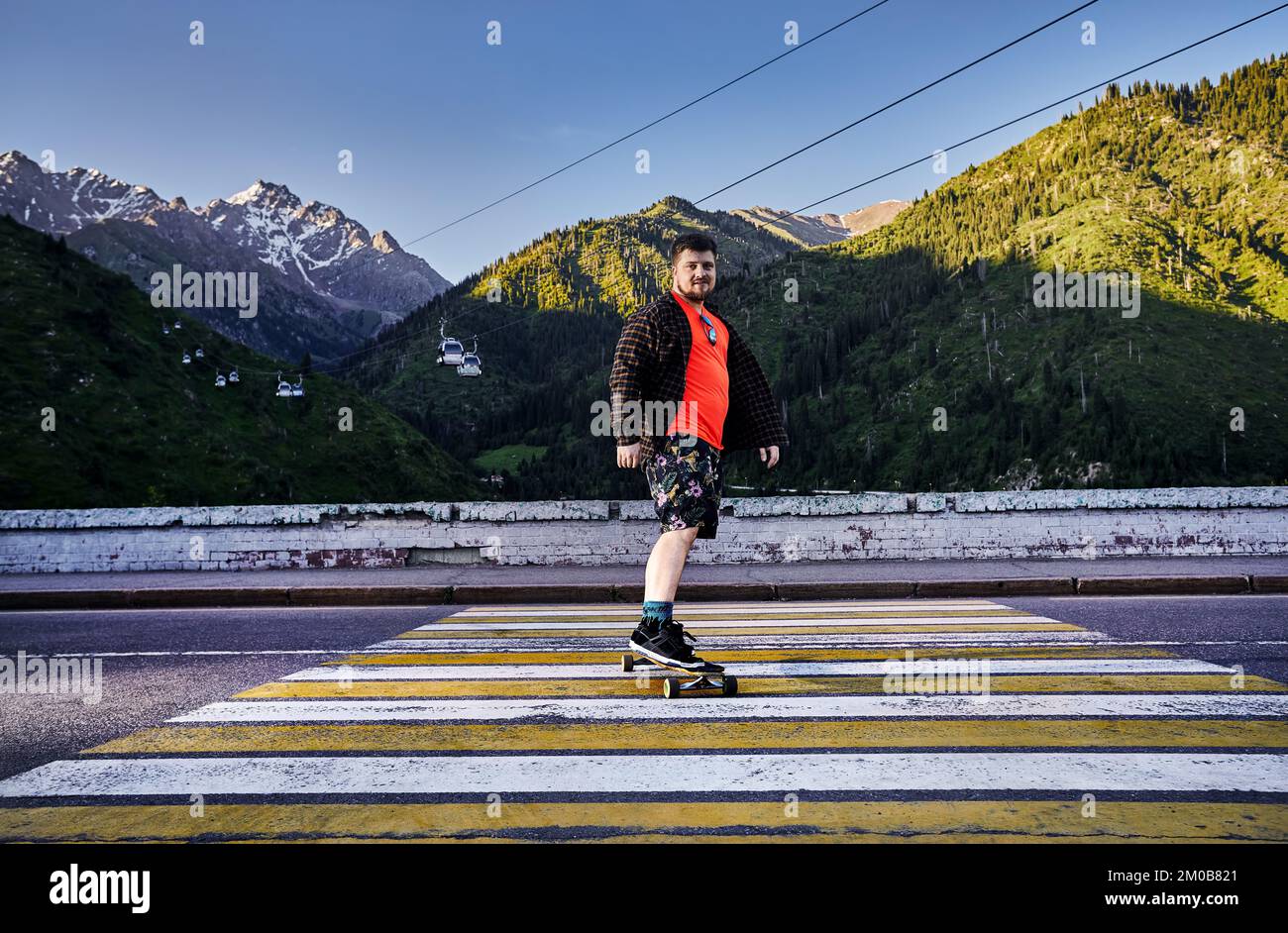 Bearded man Skater ride in the mountain road on his longboard in Medeo Dum Almaty, Kazakhstan Stock Photo