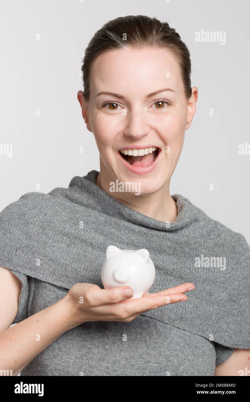 Young happy woman with a piggy bank / porcelain bank in her hand and ...