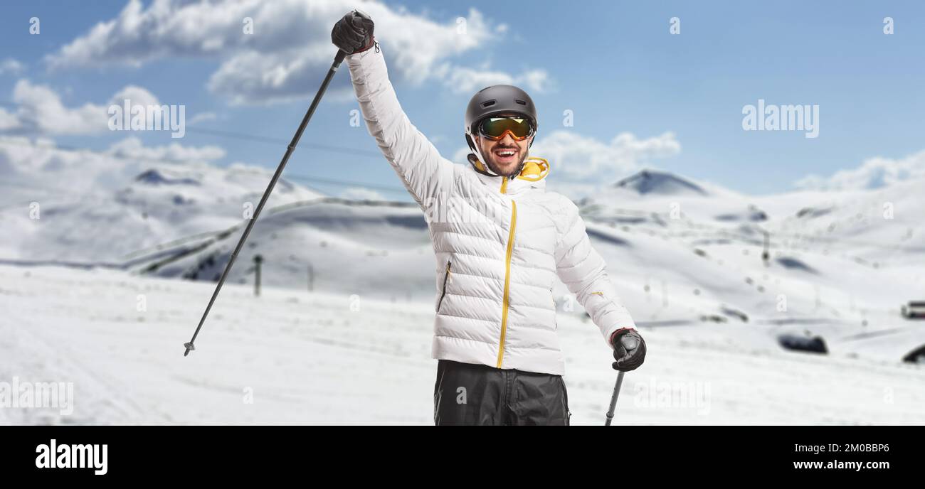 Male skier gesturing happiness with a ski pole on a ski resort Stock Photo