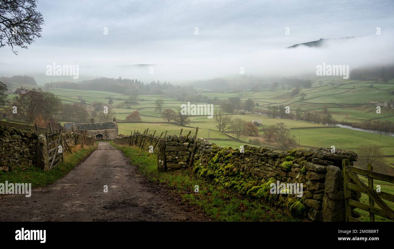 Looking beyond gates and down a farm lane towards a farm house barn in