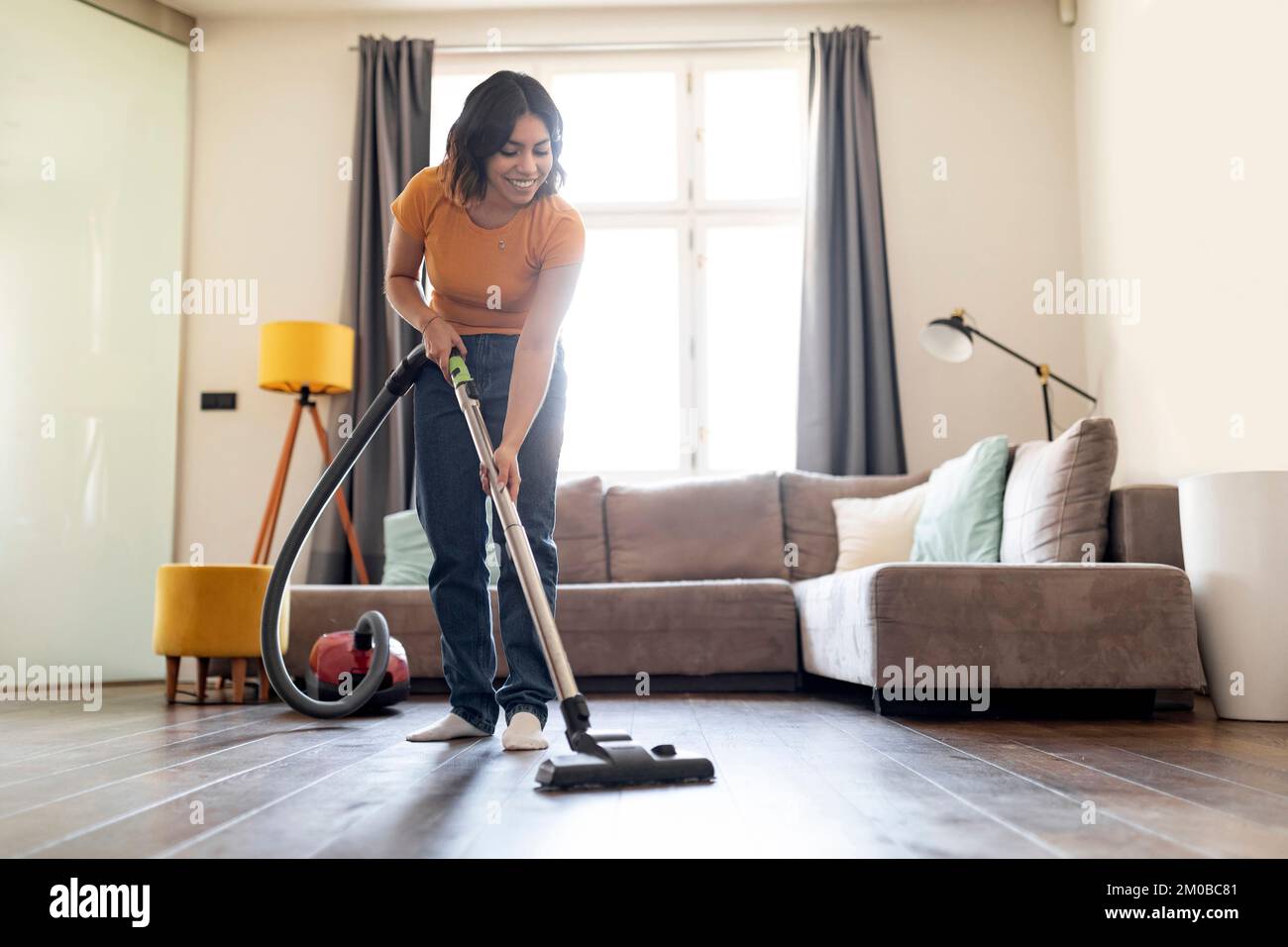 Woman Cleaning Living Room With Vacuum Cleaner Stock Photo