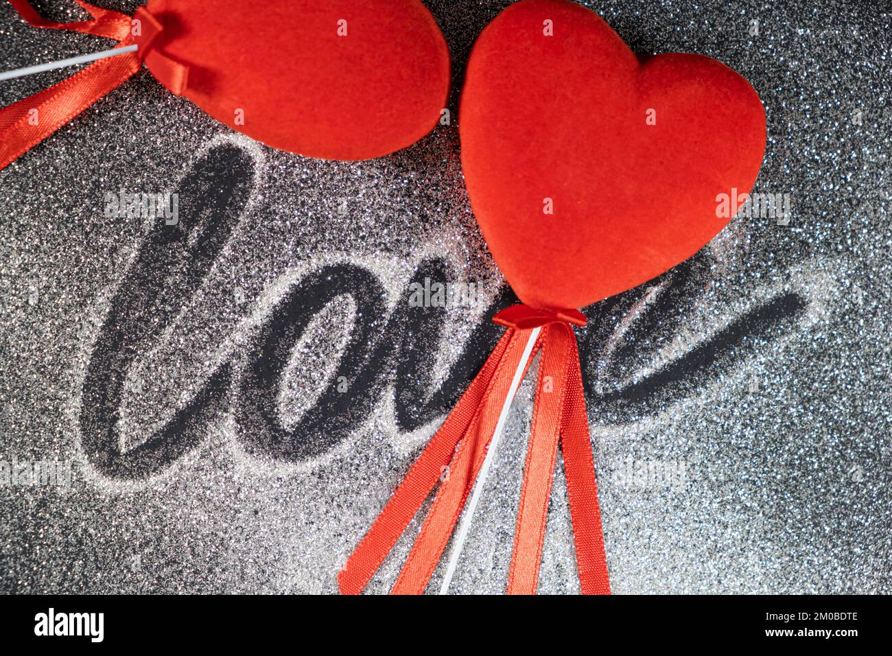Valentine's Day, two red loving hearts on a black background with sequins and the text of love. Stock Photo
