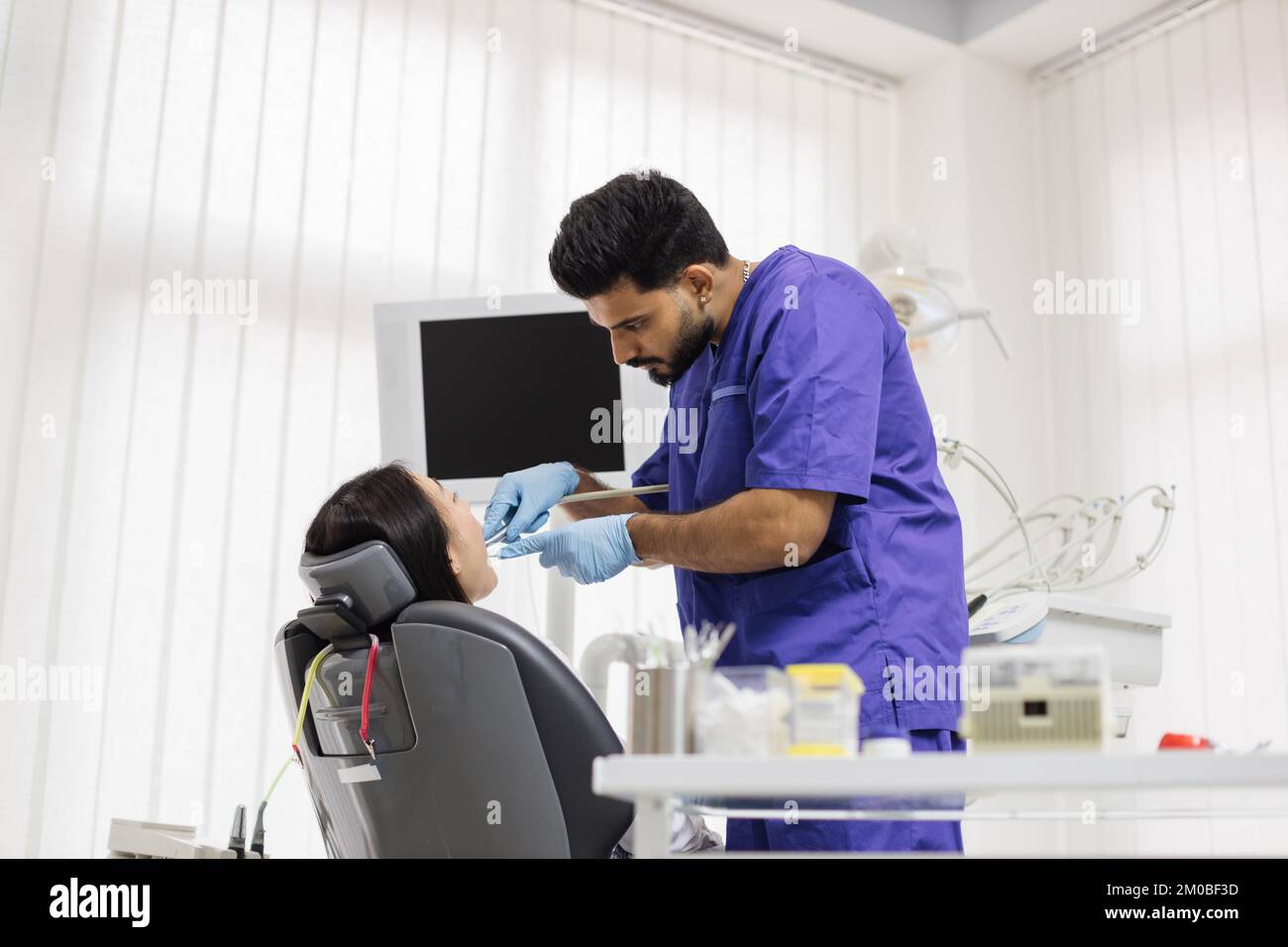 Beautiful smile with white teeth. Bearded male dentist treating teeth ...