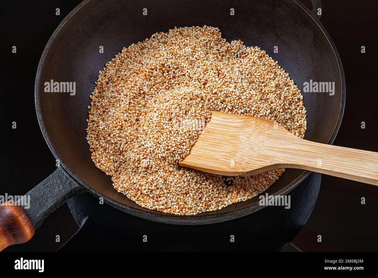 Toasting sesame seeds in a cast iron skillet. Organic benne grains