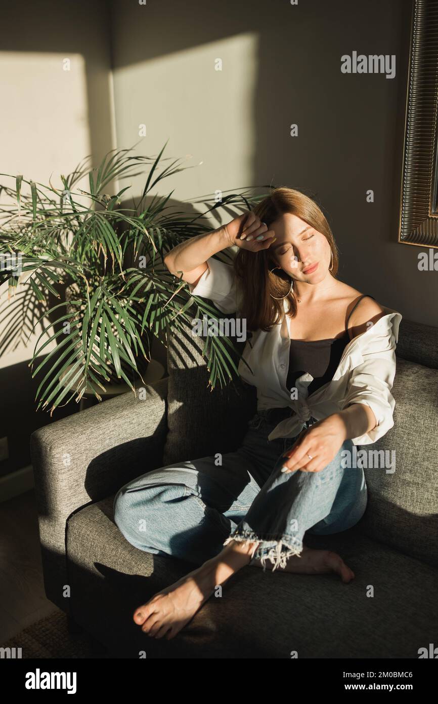 Portrait of young beautiful woman near window with shadow from flowers ...