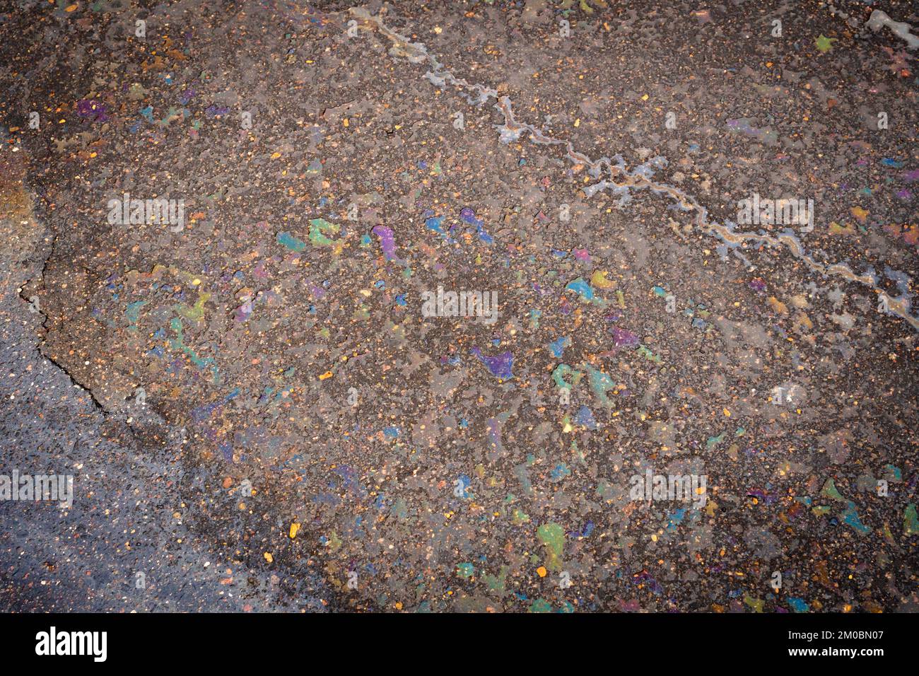Colorful gas stain on wet asphalt. Oil stain caused by a leak under a