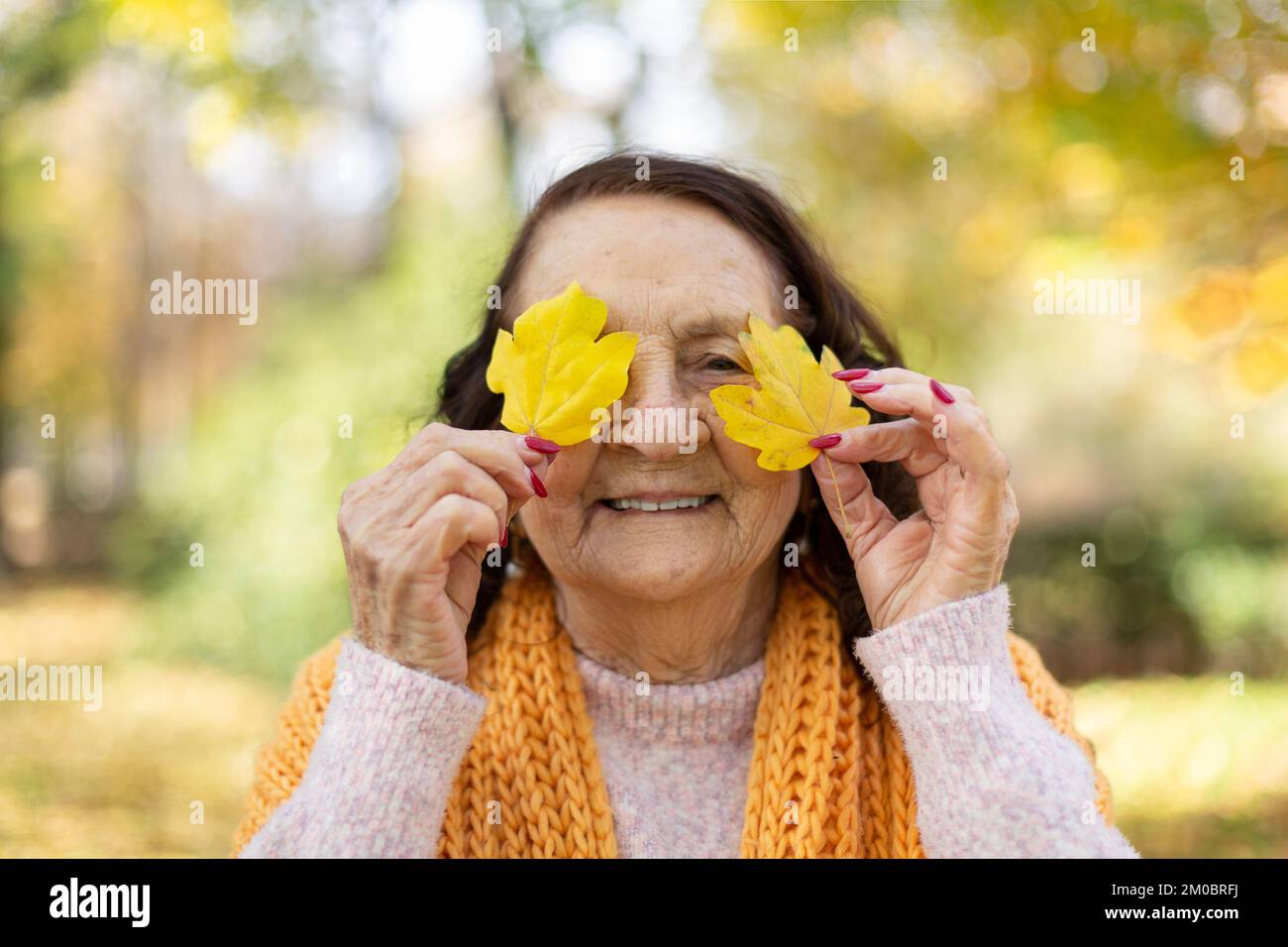 Funny portrait of old Caucasian woman in nature. Autumn season. Stock Photo