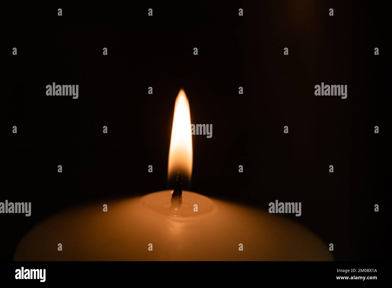 Candle burning in the dark. Stock Photo