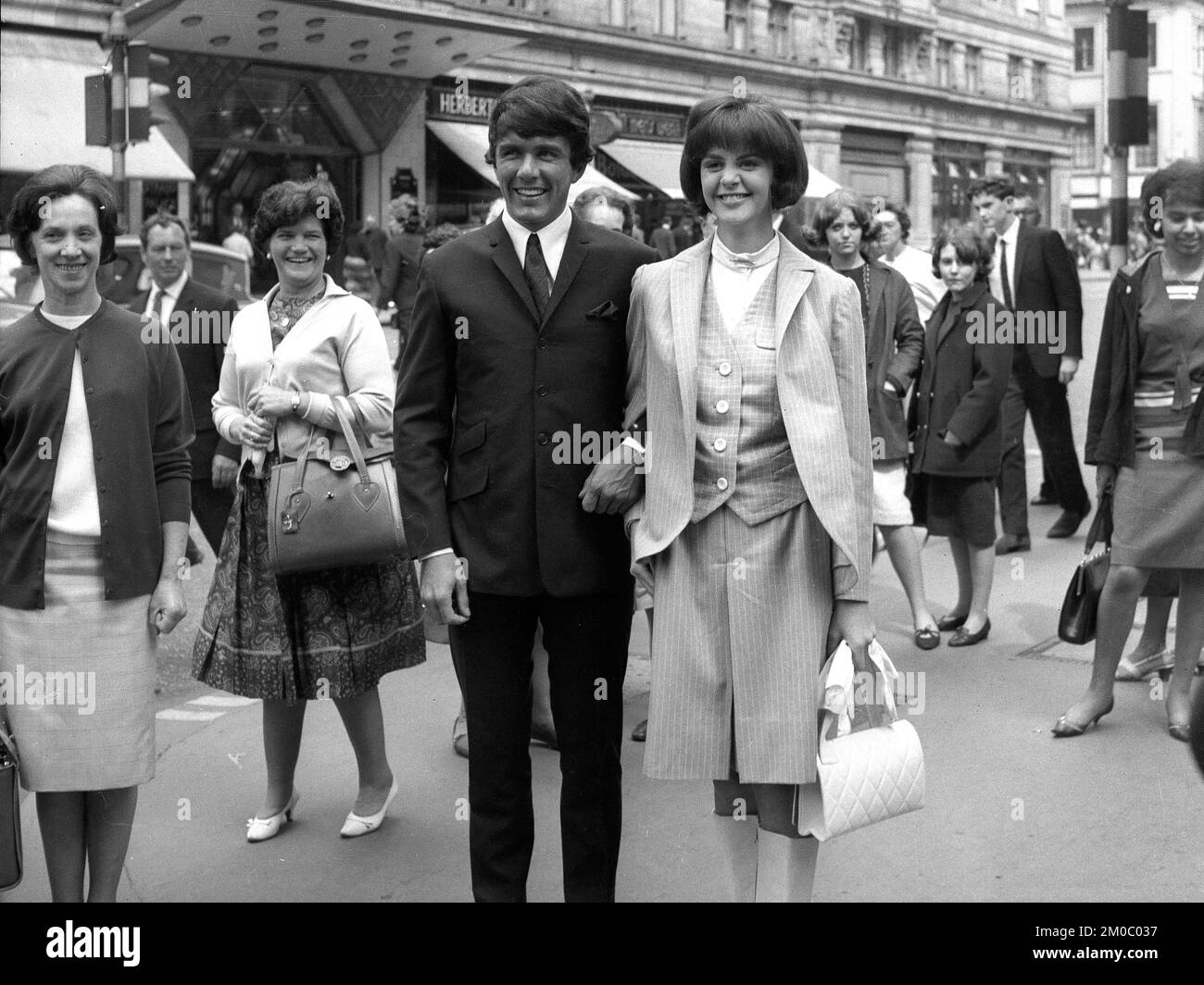 Pop star Dave Clark of the Dave Clark Five turning heads along the Strand in London 1965 with 15 year old American contest winner Kathy Sheron. She was the winner of the Revlon Natural Wonder Sweepstakes Stock Photo