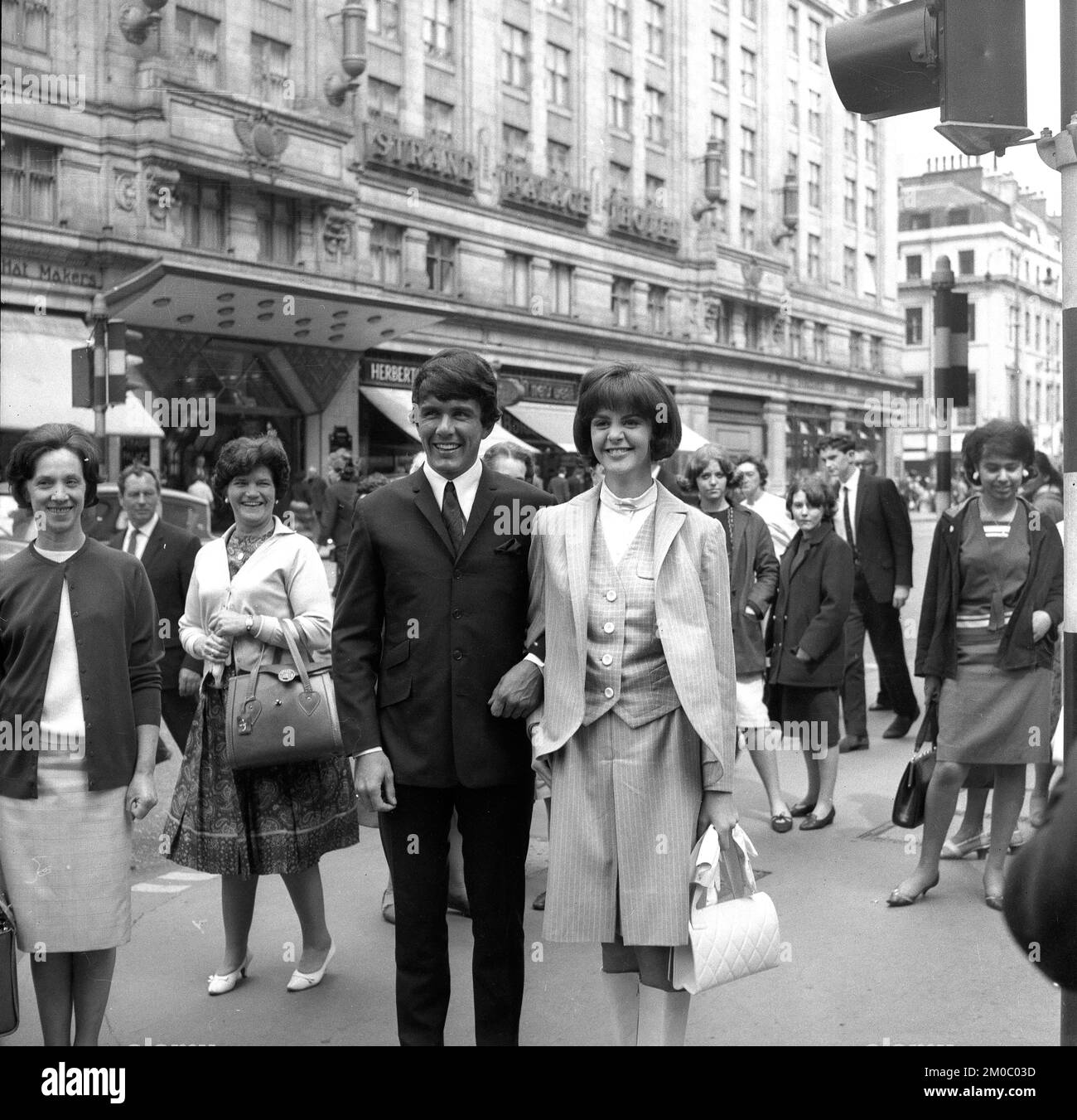 Pop star Dave Clark of the Dave Clark Five turning heads along the Strand in London 1965 with 15 year old American contest winner Kathy Sheron. She was the winner of the Revlon Natural Wonder Sweepstakes Stock Photo